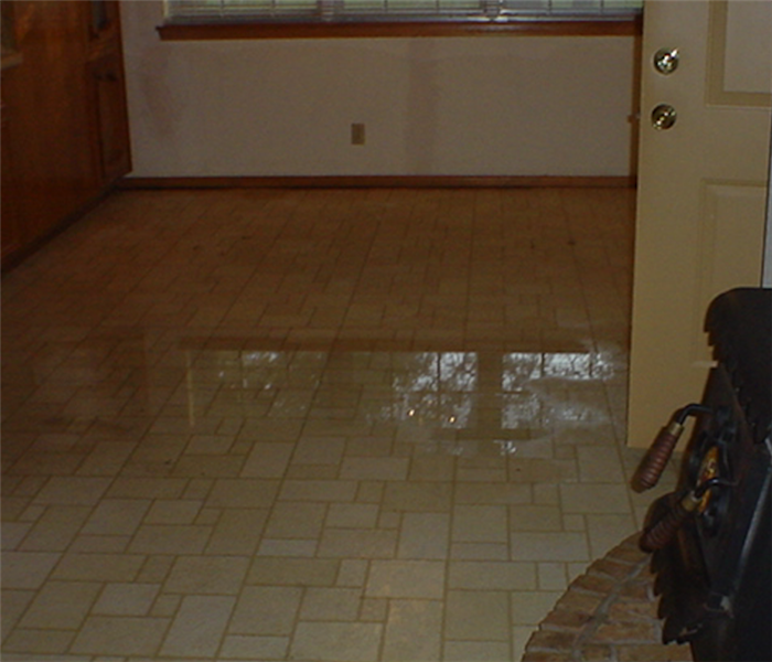 Kitchen area with pool of water in tile floor after a water loss.